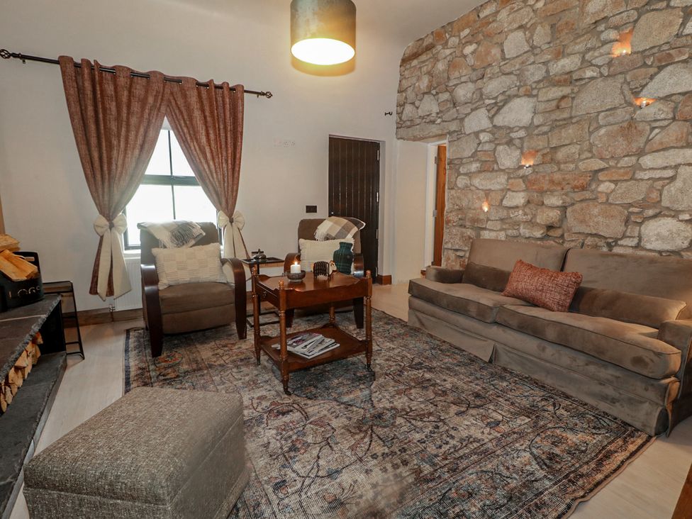 A living room with a stone wall and furniture at Hanowen House, Dungloe, County Donegal