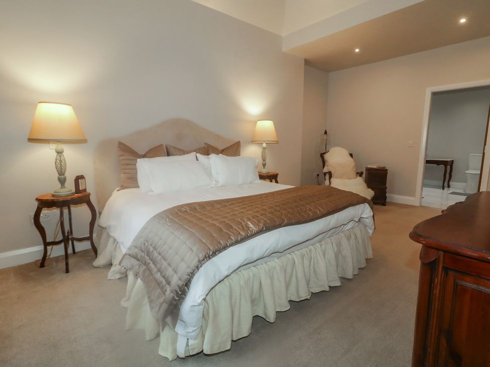 A bedroom with a bed, lamps, and chairs at Hanowen House in Dungloe, County Donegal
