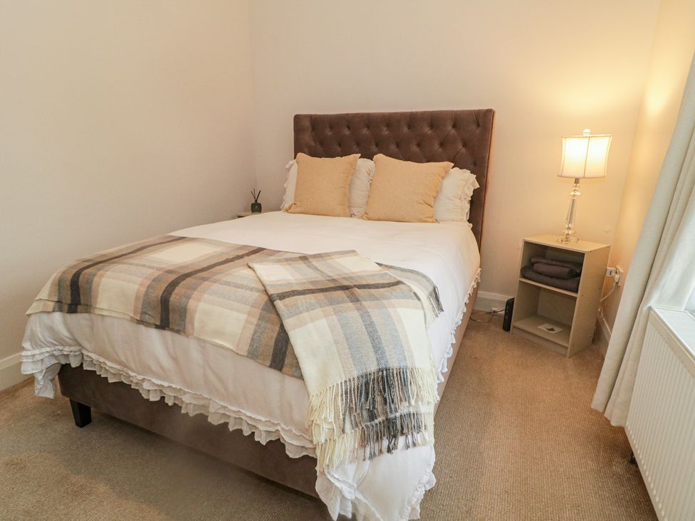 A bedroom with a bed, nightstand, and lamp at Hanowen House, Dungloe, County Donegal