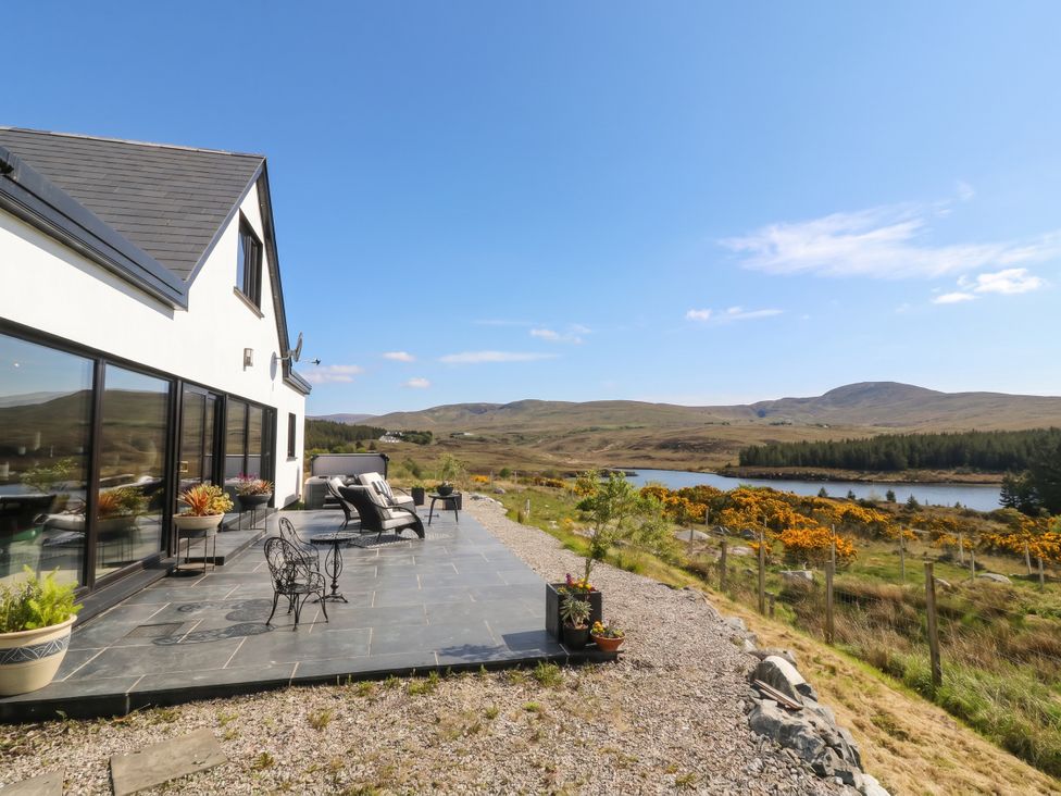 An outdoor patio area with chairs and a table overlooking a lake at Hanowen House Dungloe, County Donegal