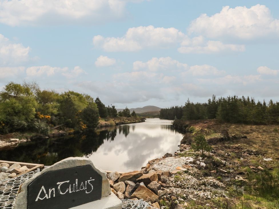 A river with surrounding trees and a sign in An Tulaigh at Hanowen House Dungloe, County Donegal