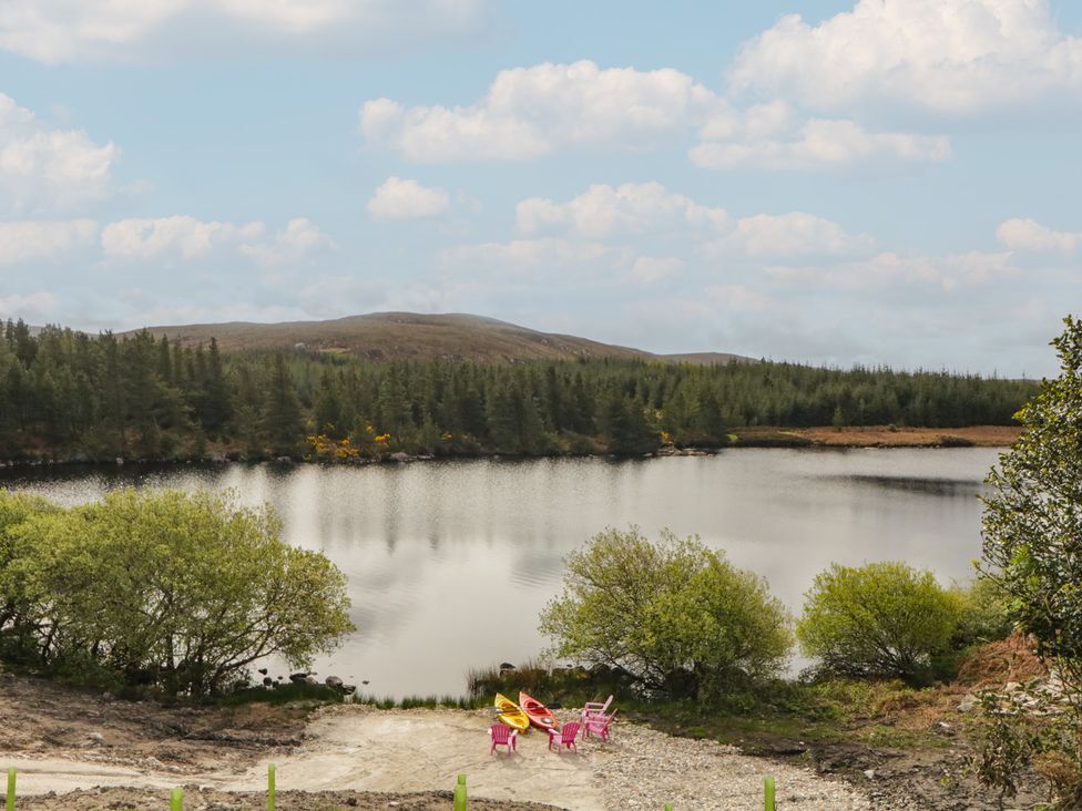 A scenic view of a lake with kayaks and chairs at Hanowen House in Dungloe, County Donegal