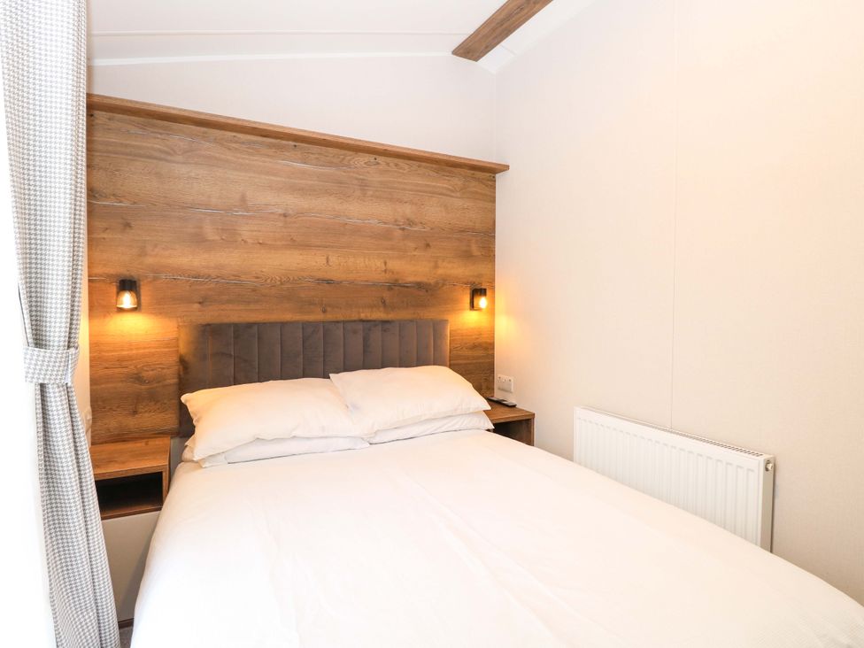 A bedroom with a bed and wooden headboard at Caravan in Great Yarmouth