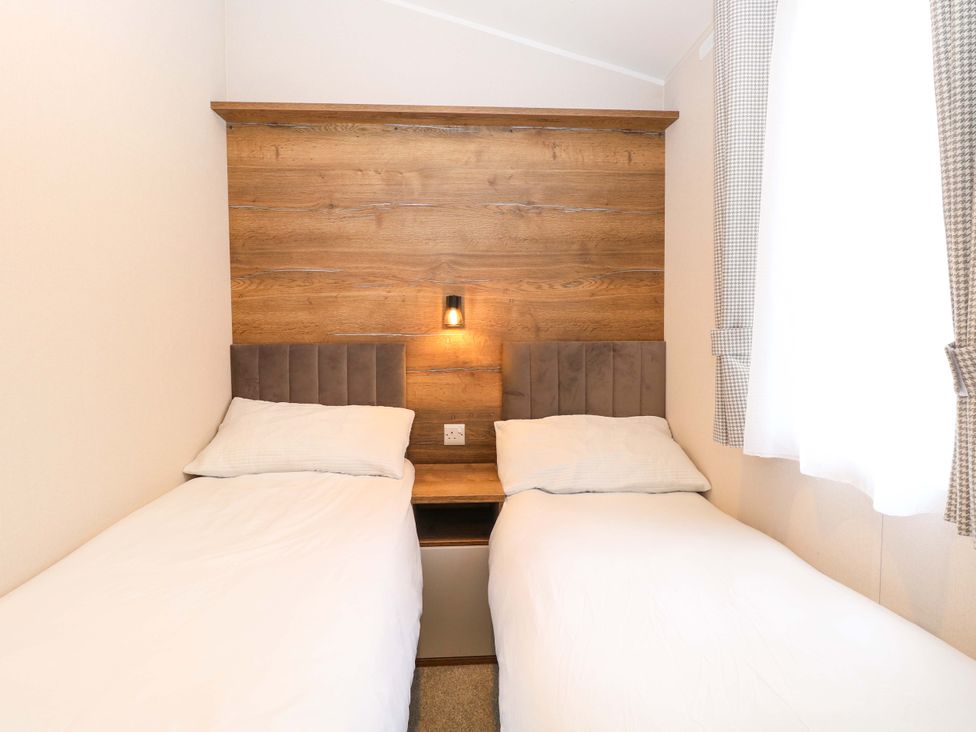 A bedroom with two beds and a wooden wall panel at Caravan in Great Yarmouth