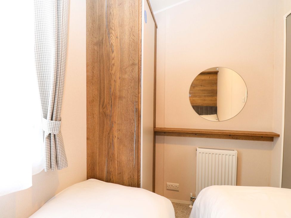 A bedroom with a wardrobe and mirror at Caravan in Great Yarmouth