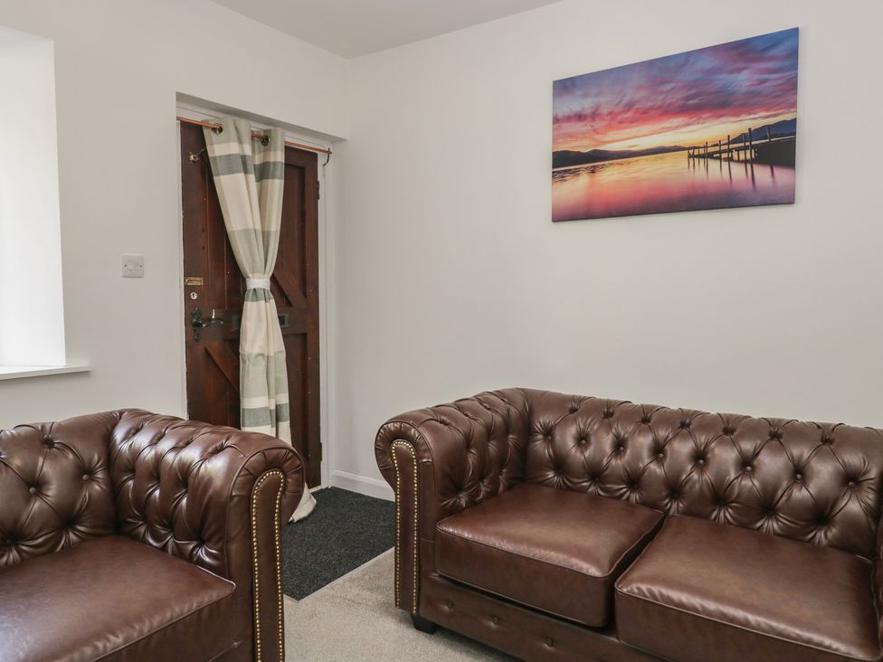 A living room with brown sofas and a door at Fellfoot Cottage