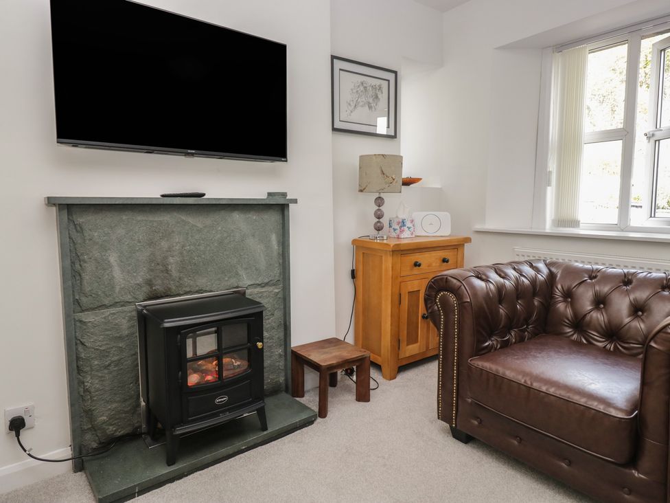 A living room with a television, fireplace, and sofa at Fellfoot Cottage in 