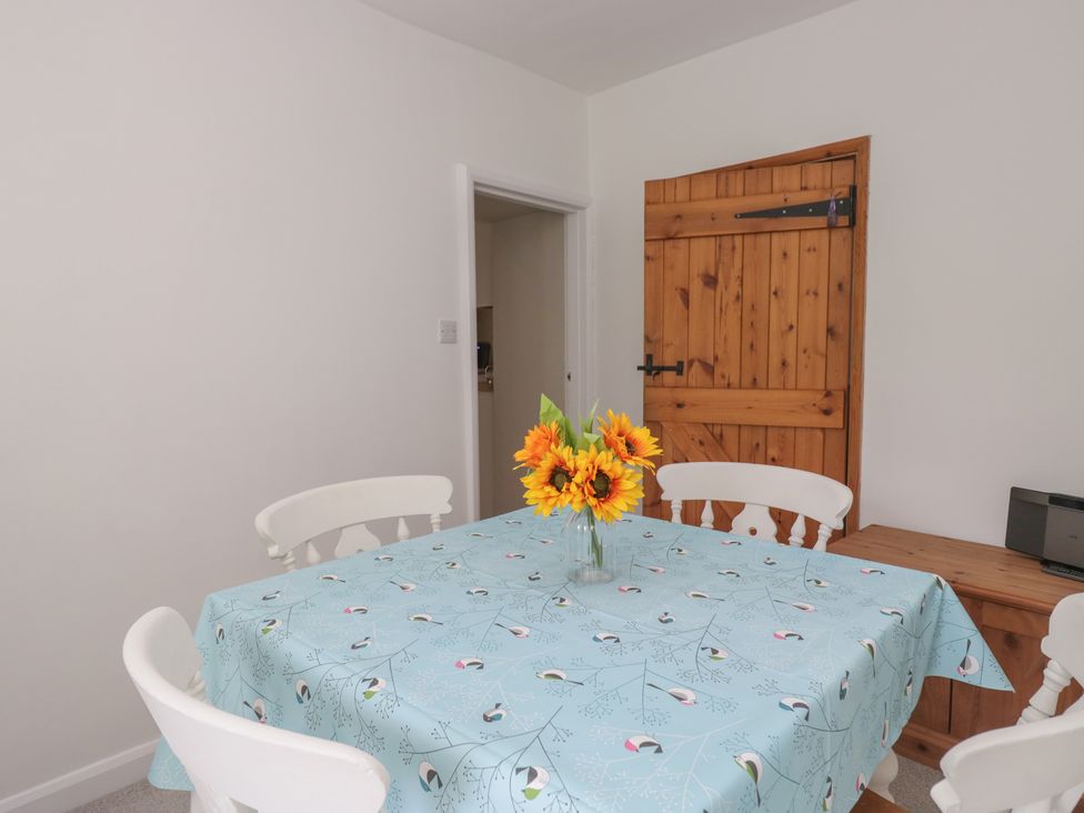 A dining room with a table and flowers at Fellfoot Cottage