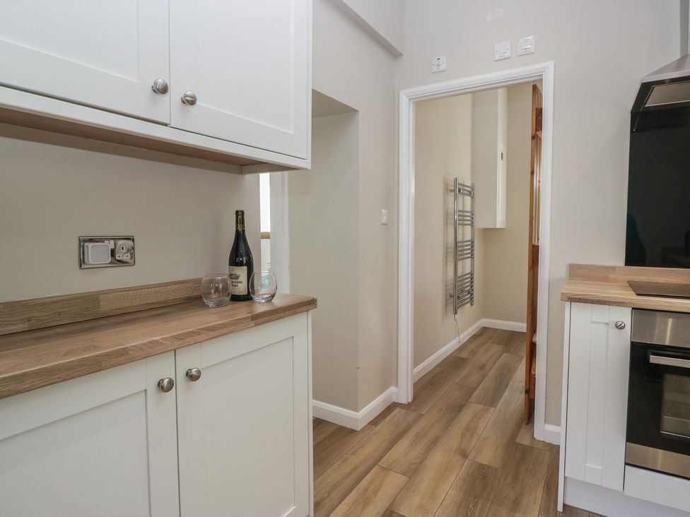 A kitchen with cabinets and a wine bottle at Fellfoot Cottage