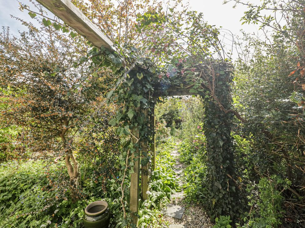 A garden pathway with an archway covered in vines at Fellfoot Cottage