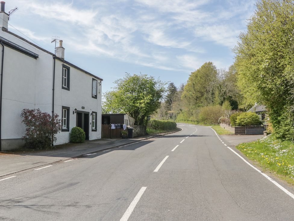 A house beside a road with trees and hedges at Fellfoot Cottage in 