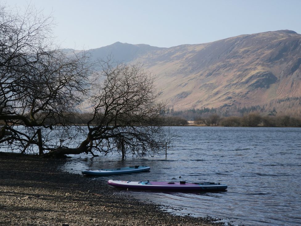 A lake with trees and kayaks by the shore at Fellfoot Cottage in 