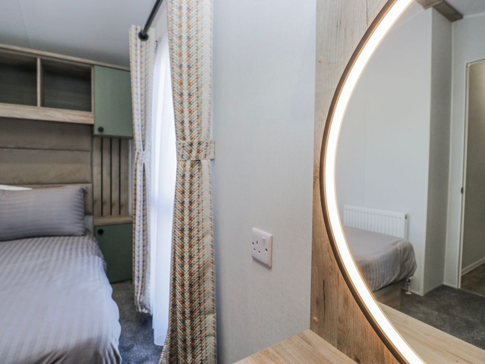 A bedroom with a bed and a mirror at Willerby High End Brand S6 (on Coniston) St Bees