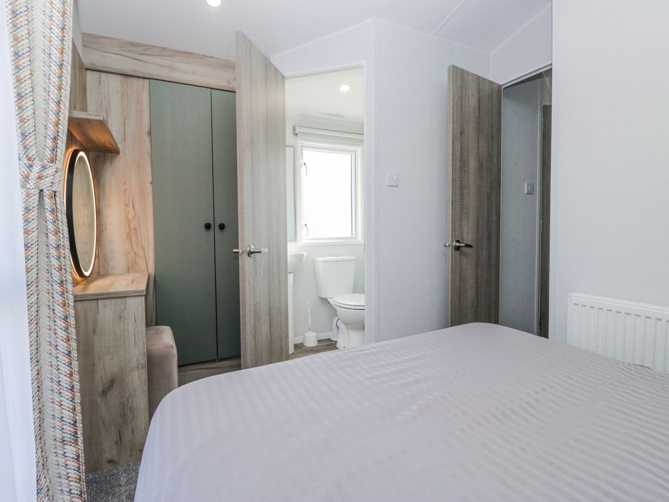 A bedroom with a bed and doors leading to a bathroom at Willerby High End Brand S6 (on Coniston) St Bees