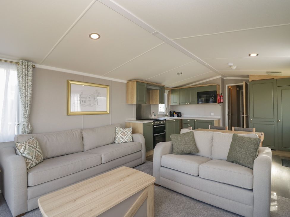 A living room with sofas and kitchen area at The Swift in St Bees