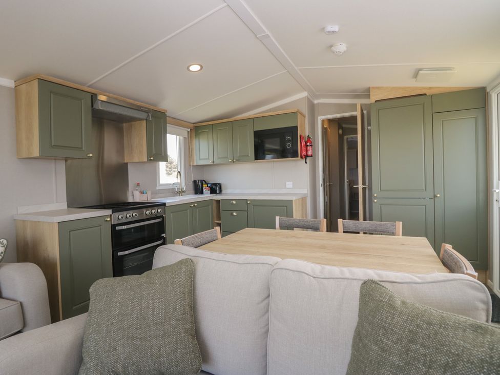 A kitchen with cabinets and dining table at The Swift in St Bees