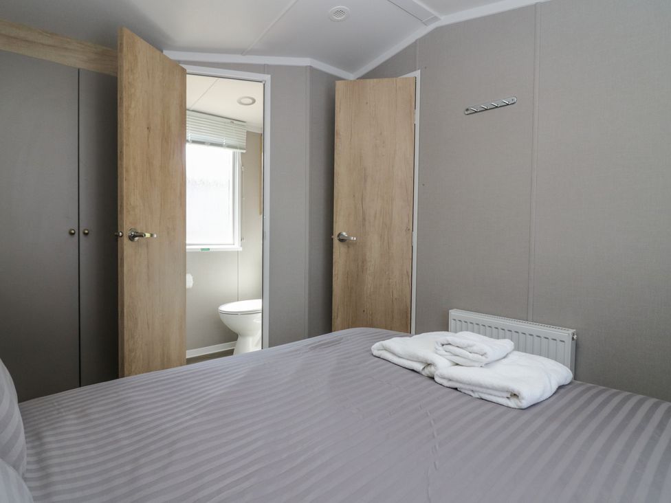 A bedroom with a bed and towels at The Swift in St Bees
