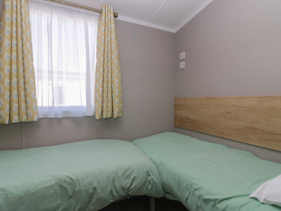 A bedroom with two beds and curtains at The Swift in St Bees