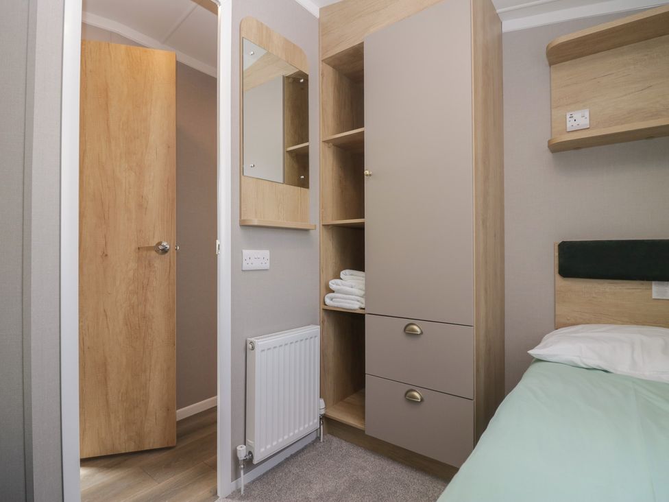 A bedroom with a wardrobe and towels at The Swift in St Bees