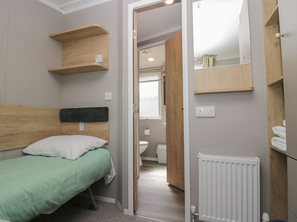 A bedroom with a bed and a door leading to a bathroom at The Swift in St Bees