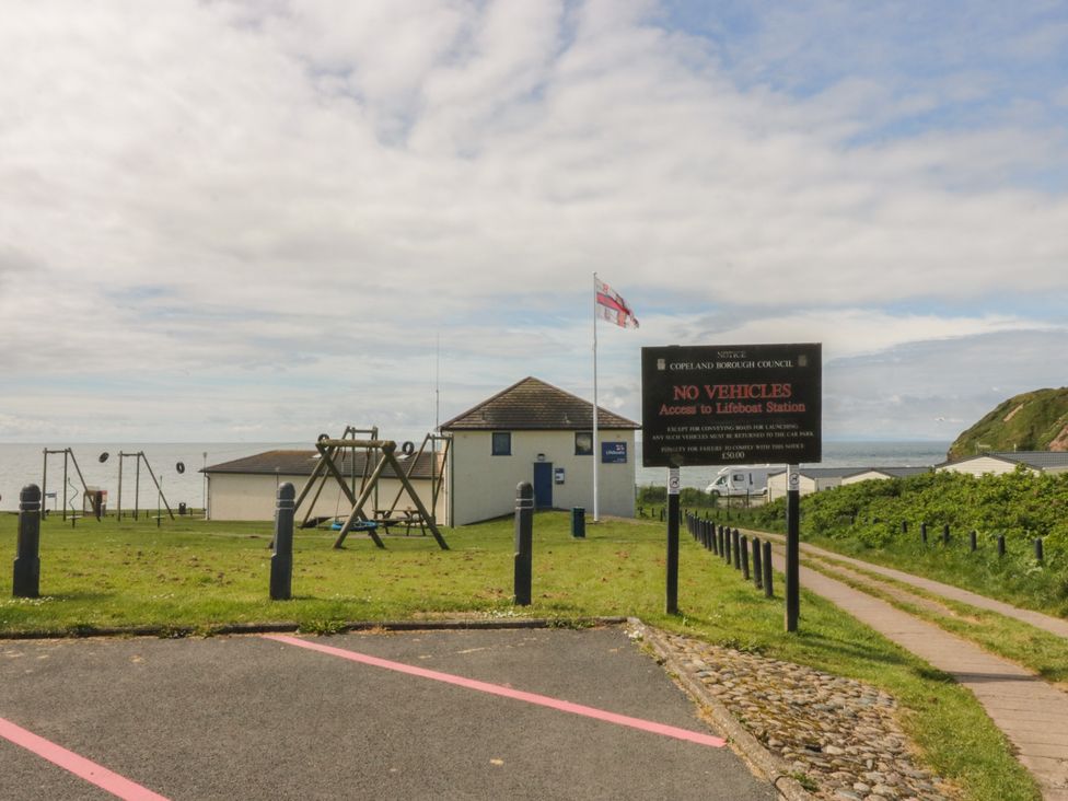 A playground with swings and a building near the ocean at The Swift in St Bees