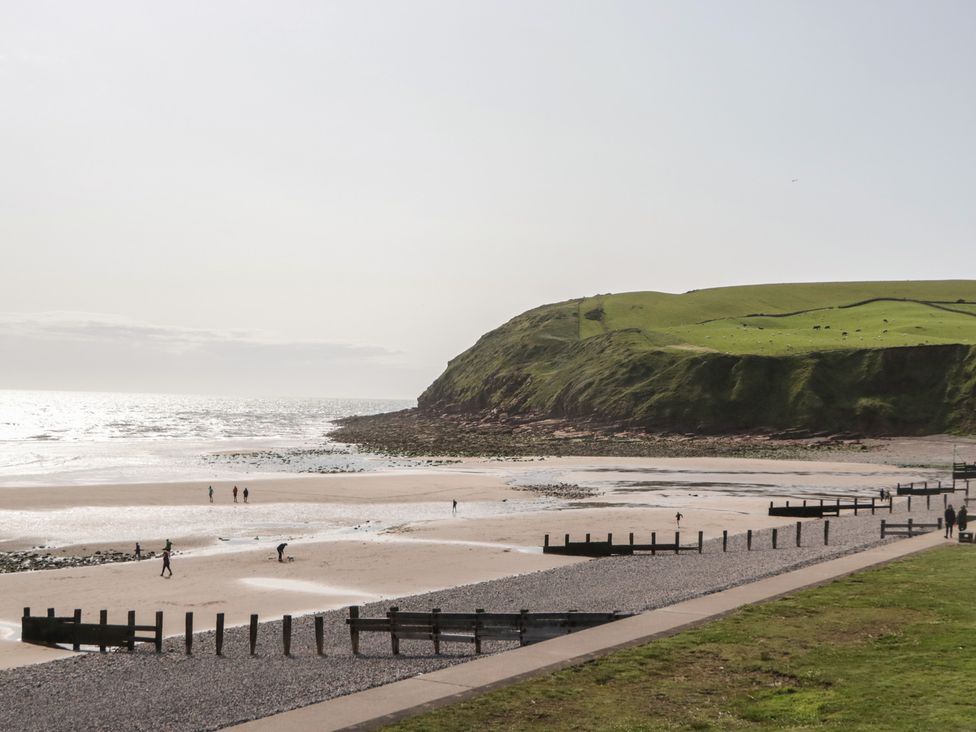 A beach with people walking and a cliff in the background at Swift Brand (3 Bed) (on Coniston) St Bees