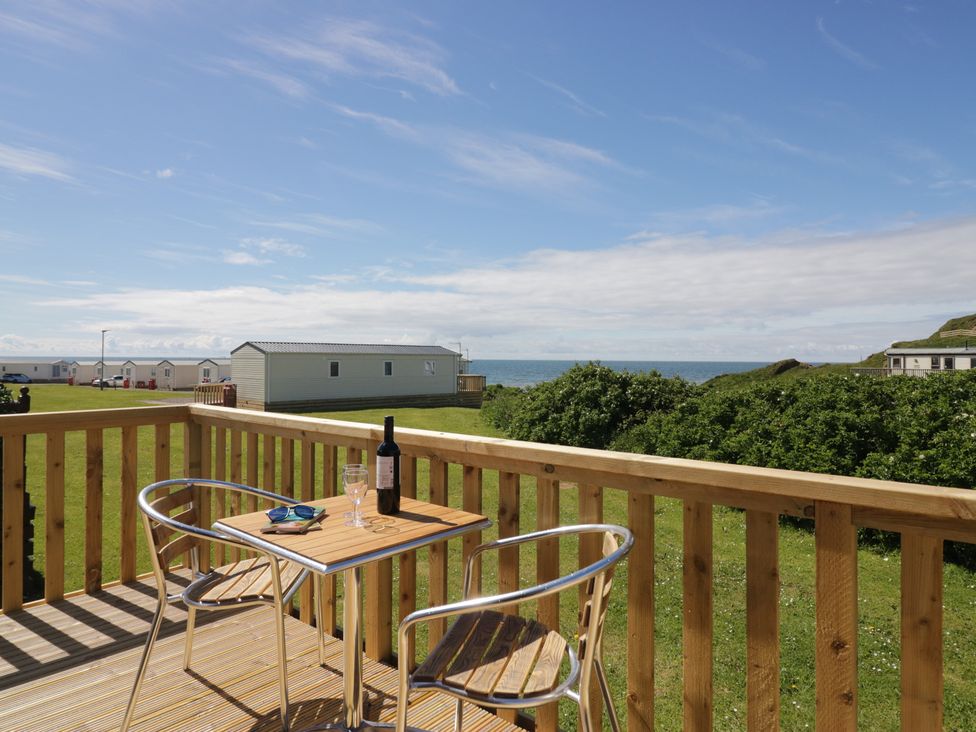 A balcony with a table and chairs overlooking the sea at The Plover in St Bees