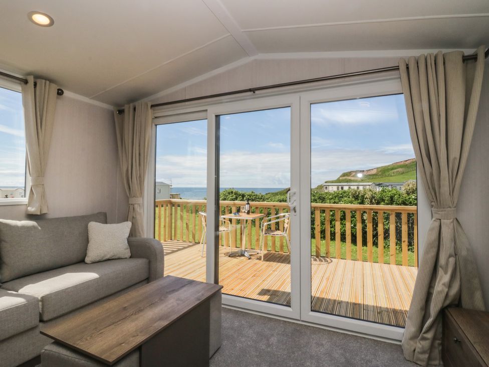 A living room with sliding doors leading to a deck at The Plover in St Bees