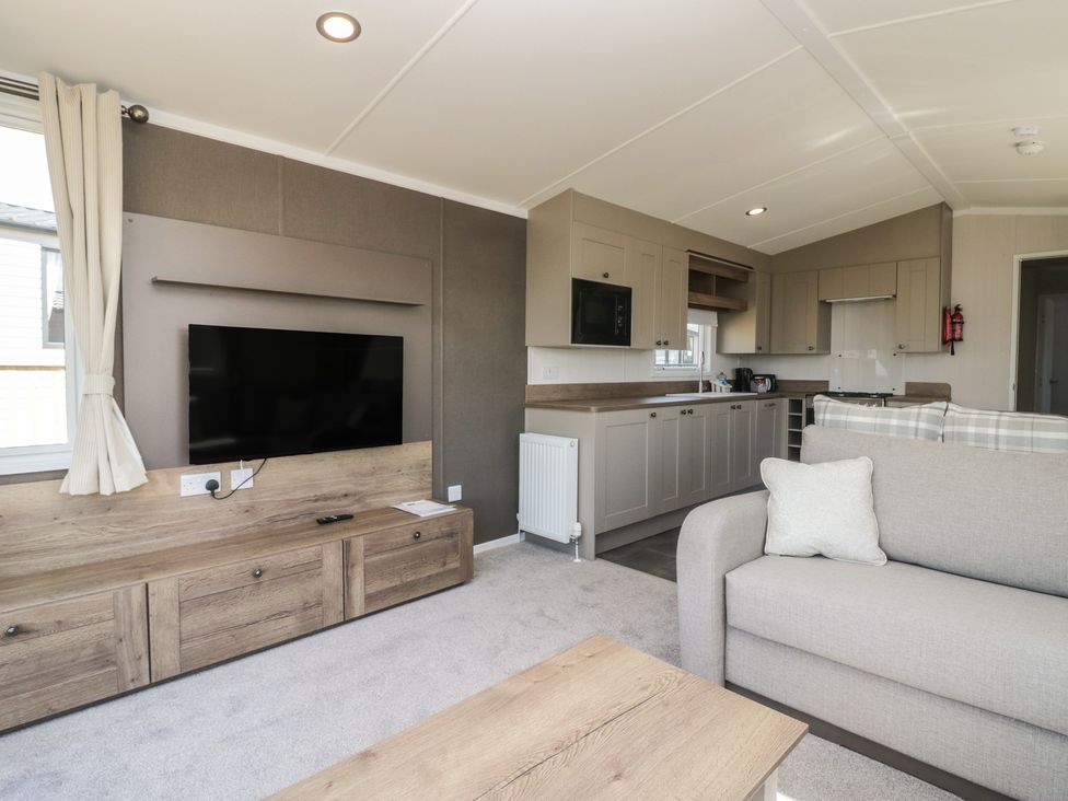 A living room with a television and kitchen units at The Plover in St Bees