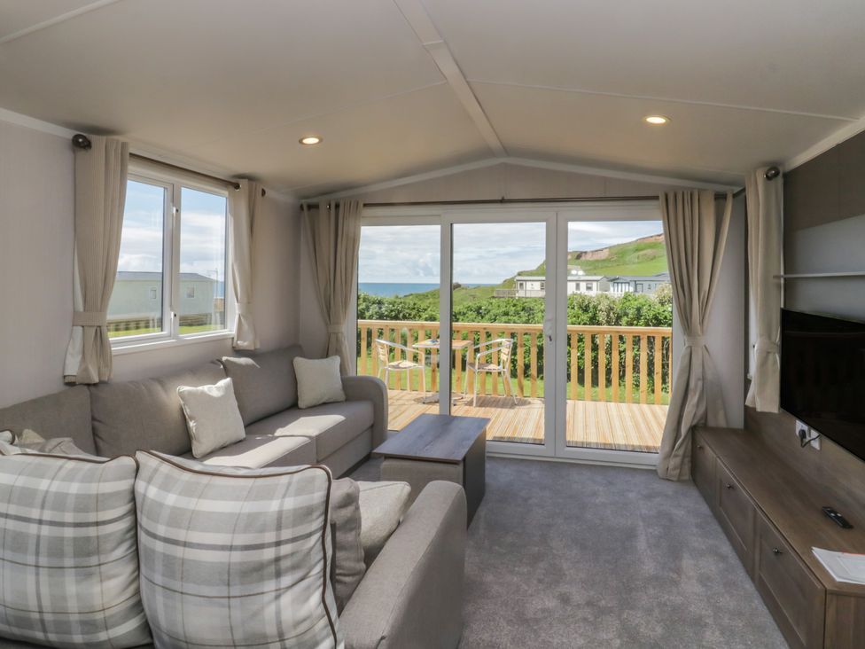 A living room with a sofa and windows at The Plover in St Bees