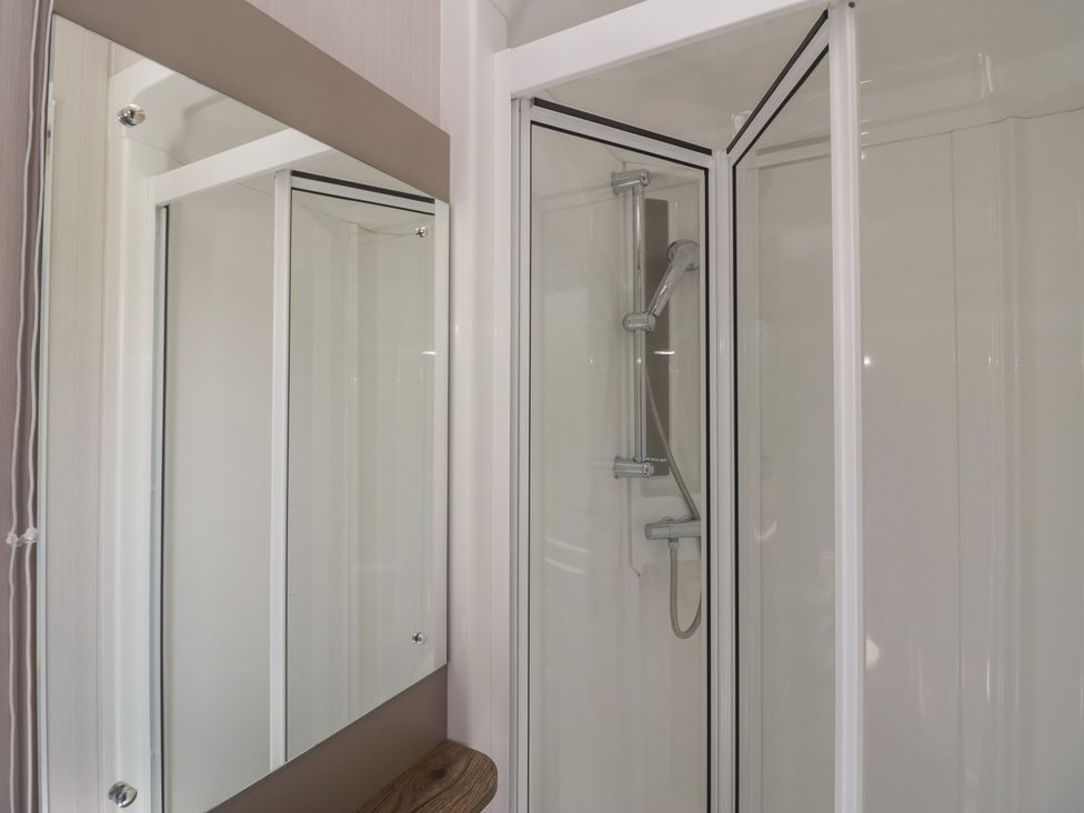 A shower enclosure with mirror in a bathroom at The Plover in St Bees