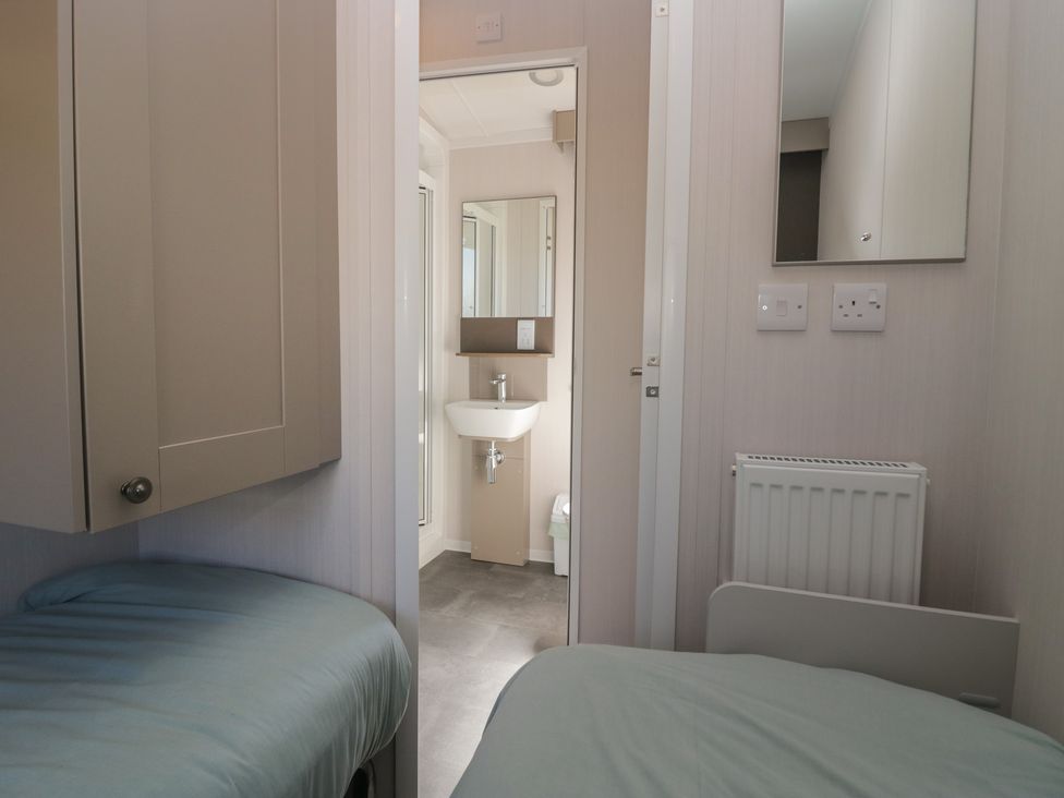 A bedroom with beds and an adjoining bathroom at The Plover in St Bees