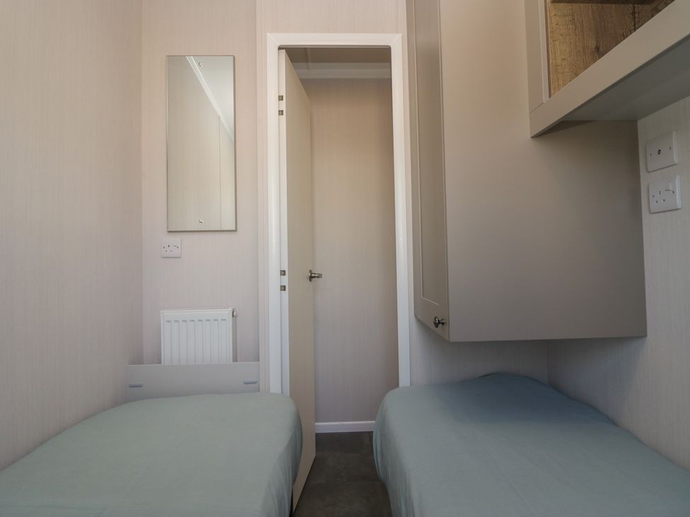 A bedroom with two beds and a mirror at The Plover in St Bees