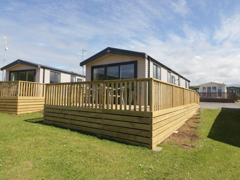 A caravan with decking and grass area at The Plover St Bees