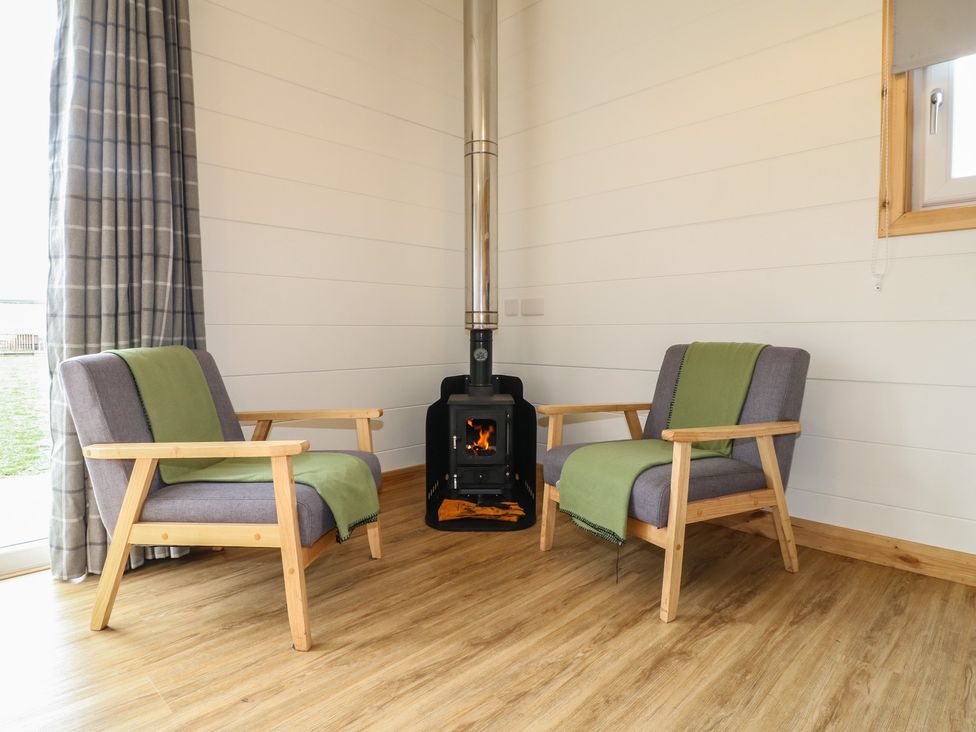 Two armchairs and a stove in a living room at Sherwood - Cosy Pod 1