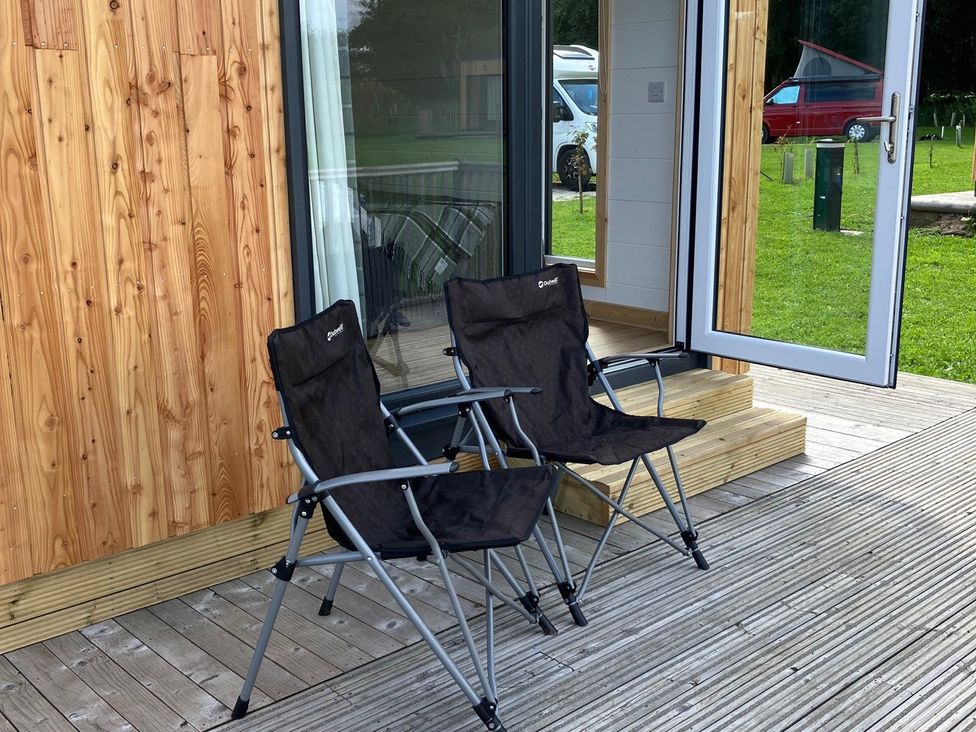 Two folding chairs on a deck outside a wooden building at Sherwood - Cosy Pod 1