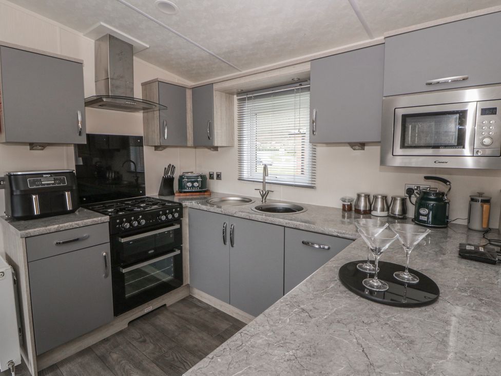 A kitchen with cabinets, stove, oven, sink and microwave at The Ridgeway in New Quay