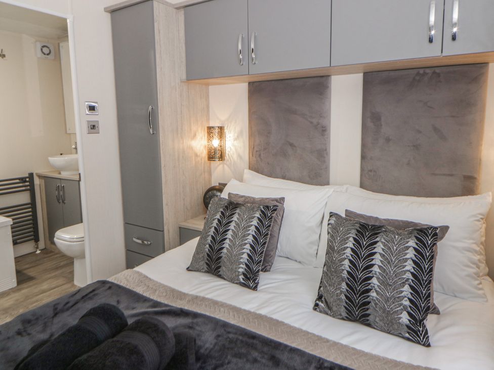 A bedroom with a bed, cushions, wardrobe, and en-suite bathroom at The Ridgeway in New Quay