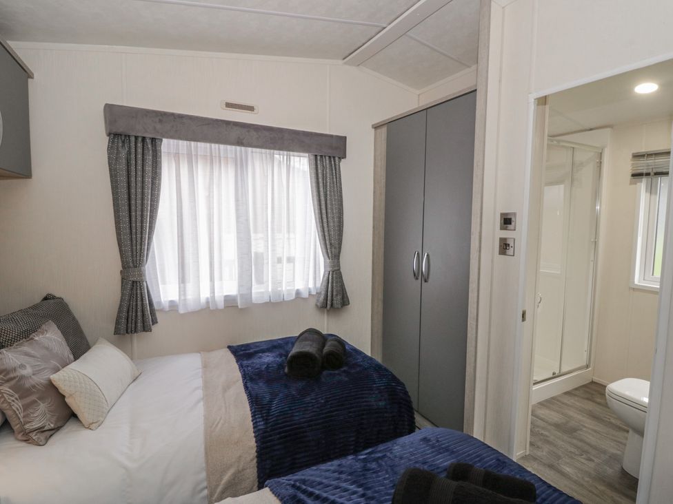 A bedroom with two beds and a wardrobe at The Ridgeway in New Quay