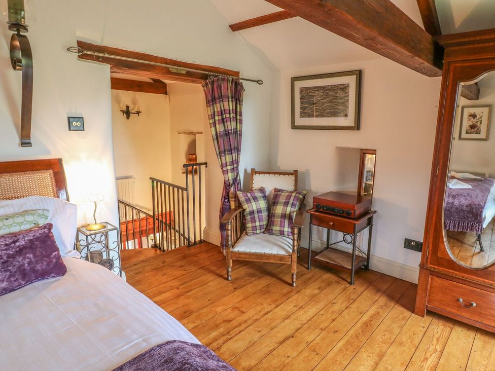 A bedroom with a bed, chair, and table at The Bothy in Leyburn