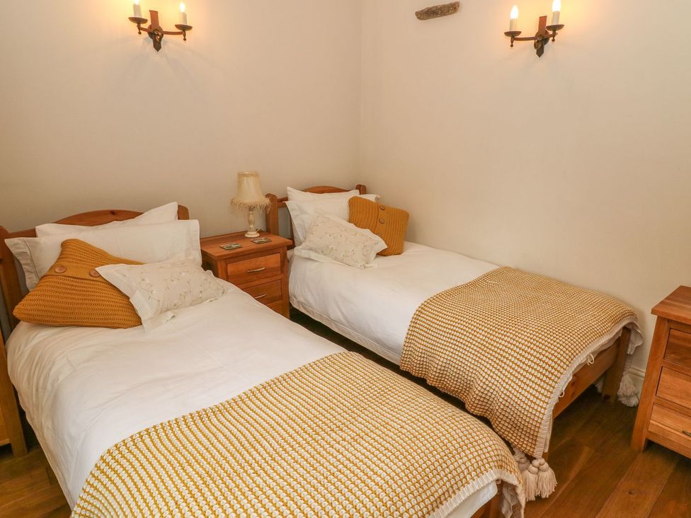 A bedroom with two single beds and a nightstand at The Bothy in Leyburn