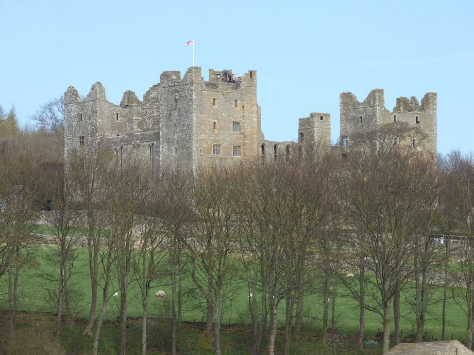 A castle with ruins and trees in the foreground at The Bothy in Leyburn