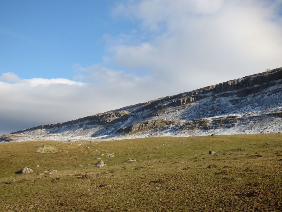 A landscape with grass and snow on a rocky slope at The Bothy Leyburn