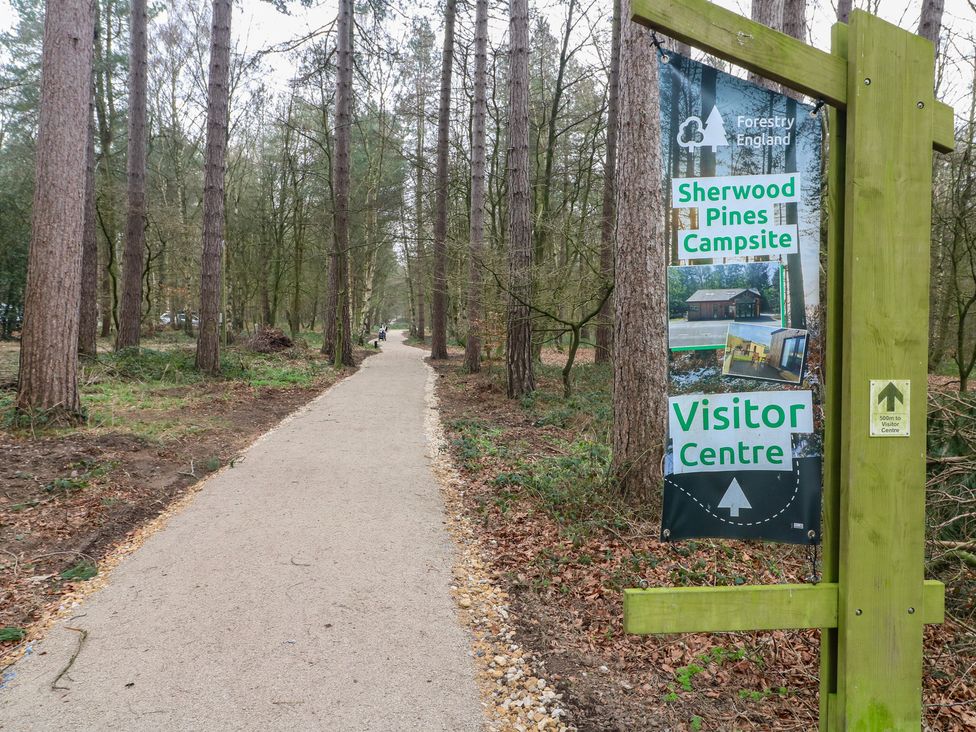 A walking path with a sign for Sherwood Pines Campsite and Visitor Centre in a forested area