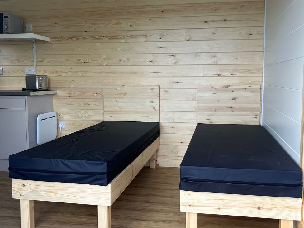 A bedroom with two beds and a shelf at Sherwood Pines - Cosy Pod 2 near Edwinstowe