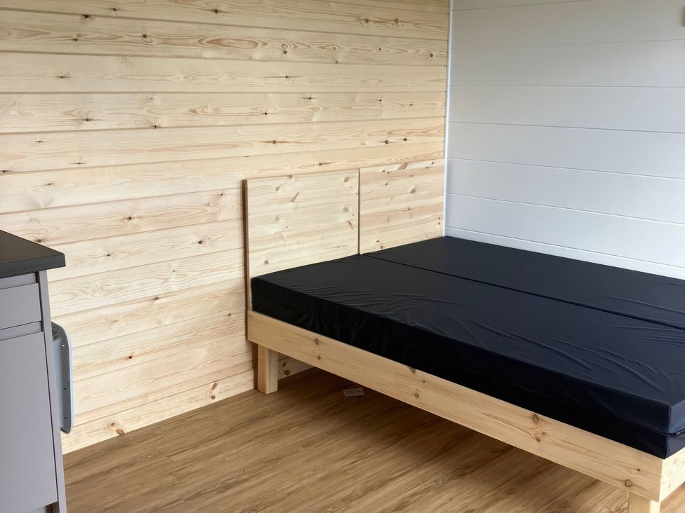 A bedroom with a bed and wooden paneling at Sherwood Pines - Cosy Pod 2 near Edwinstowe