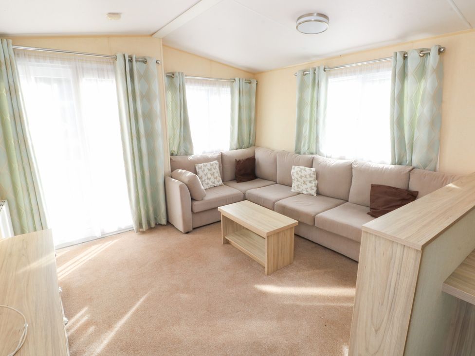 A living room with a sofa and coffee table at Under cliff caravan in Ferryside