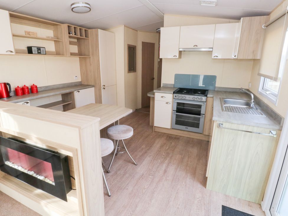 A kitchen with a table and stools and appliances at Under cliff caravan Ferryside