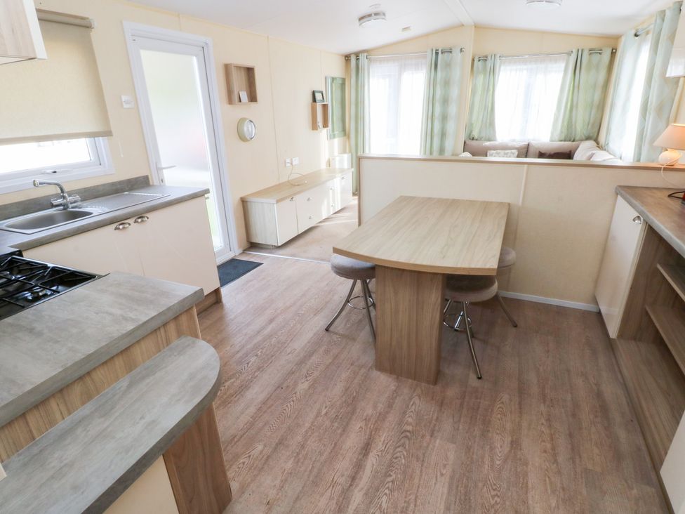 A kitchen with a dining table and chairs at Under cliff caravan Ferryside
