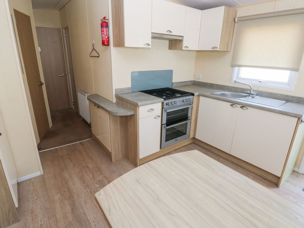 A kitchen with oven and sink at Under cliff caravan in Ferryside